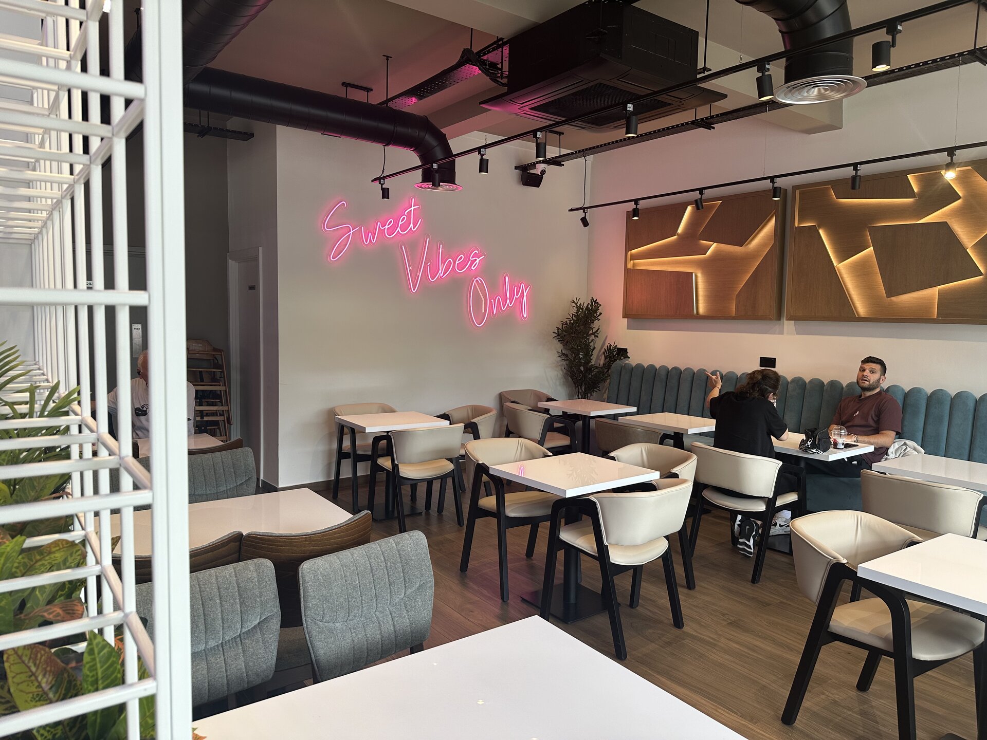 'Sweet Vibes Only' neon sign above the dining tables
